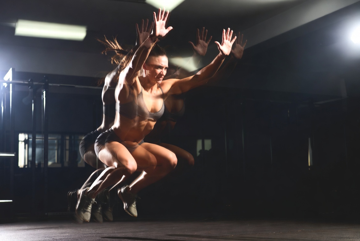 Person mid-burpee explosive jump with dramatic lighting